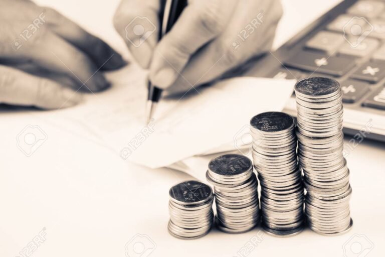 manos sosteniendo monedas sobre una calculadora 1