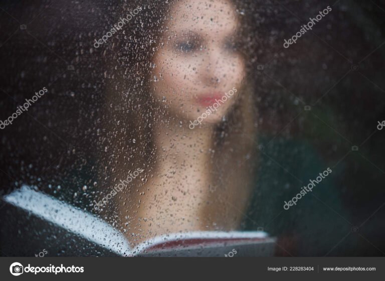 persona leyendo junto a una ventana lluviosa