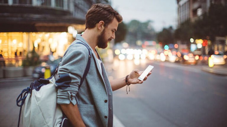Cómo puedo saber si tengo multas de tránsito en línea 7 persona revisando su telefono en la calle