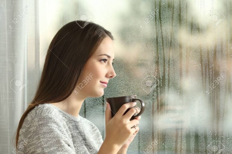 una persona mirando por la ventana pensativa